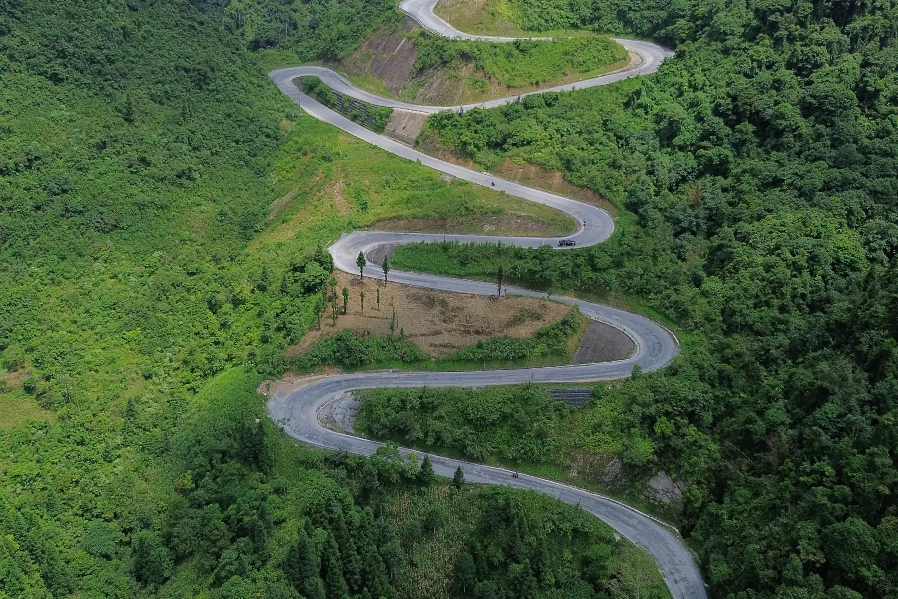 A winding mountain road across green slopes in Ha Giang