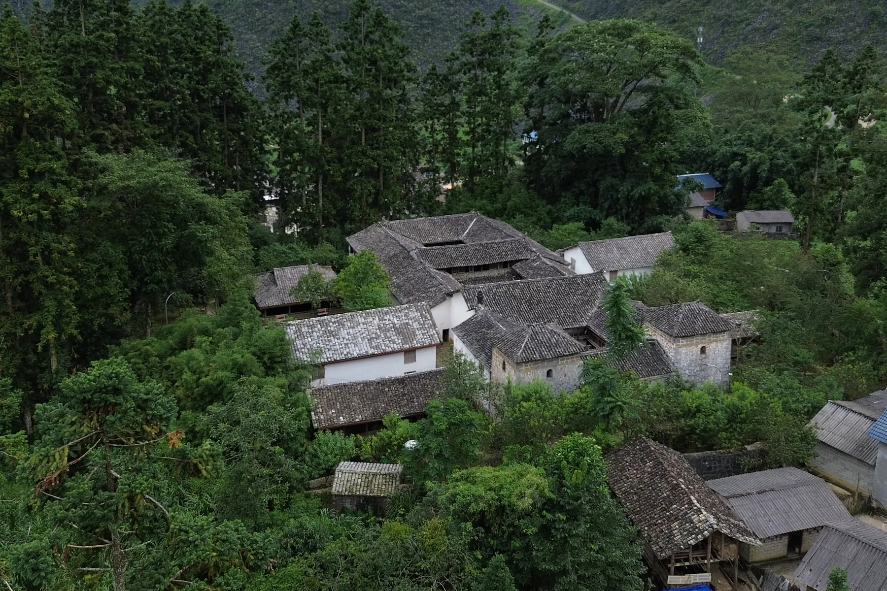 Traditional tiled-roof houses below green mountains on the karst plateau