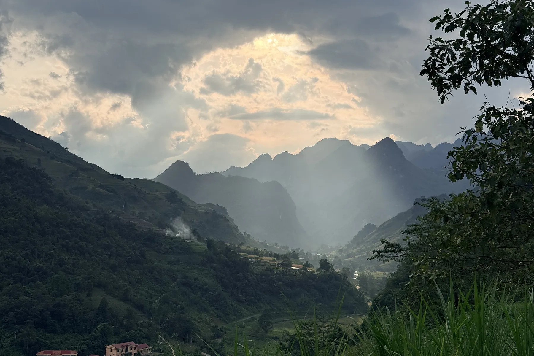 Sunlight breaking through clouds over a Ha Giang mountain valley after rain