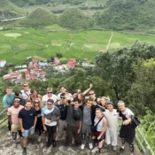 Travellers overlooking a green valley from a viewpoint in Ha Giang