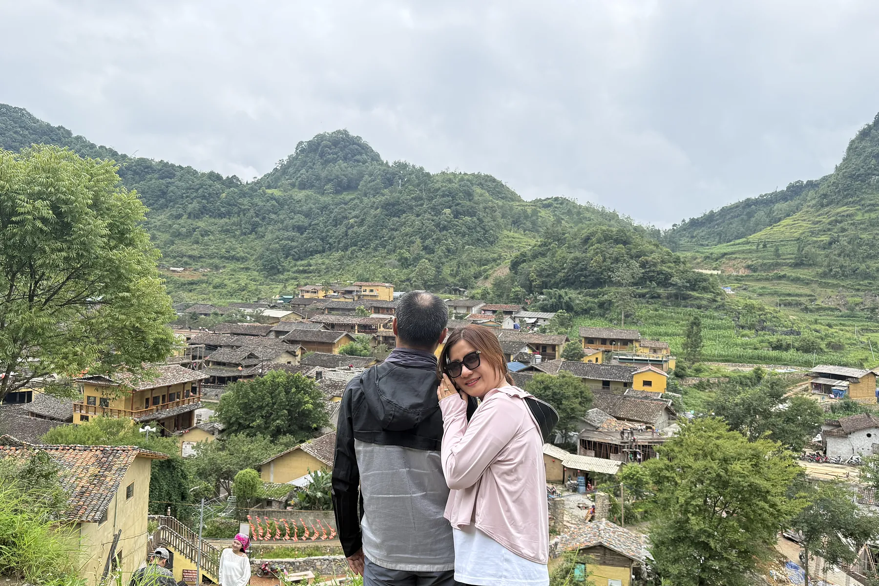 Travellers overlooking a highland village and green fields in Ha Giang