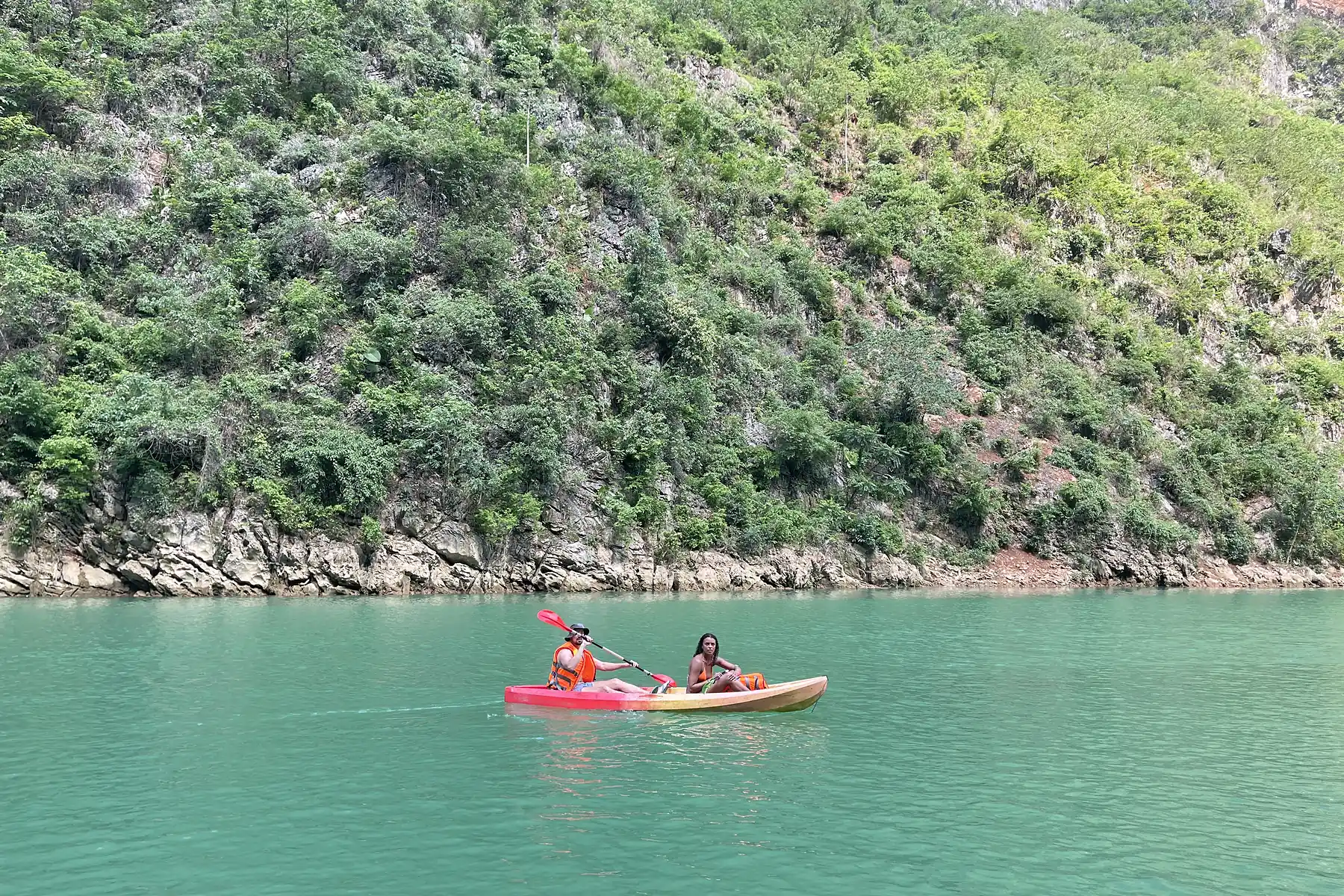 Two travellers kayaking on the Nho Que River between Ha Giang's limestone mountains