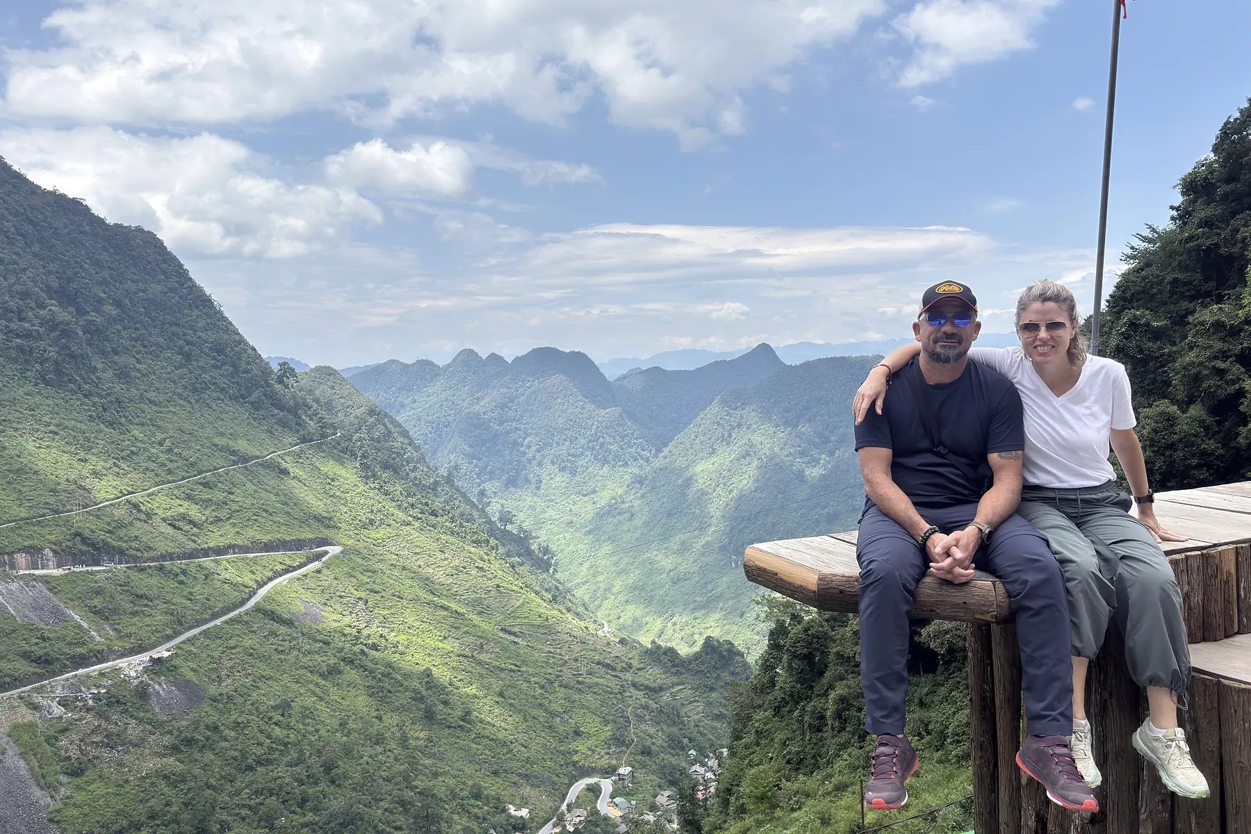 Two travellers resting at a viewpoint on a Ha Giang mountain pass